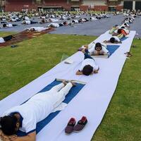 Neu Delhi, Indien, Juni 21, 2023 - - Gruppe Yoga Übung Session zum Menschen beim Yamuna Sport Komplex im Delhi auf International Yoga Tag, groß Gruppe von Erwachsene Teilnahme Yoga Klasse im Kricket Stadion foto