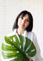 Frau aus dem Nahen Osten, die Badetücher trägt und ein grünes Monstera-Blatt hält foto