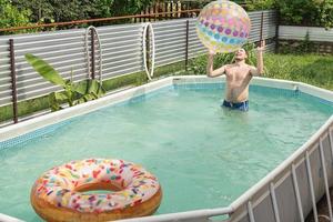 Mann hat Spaß im Schwimmbad und spielt mit aufblasbarem Ball foto