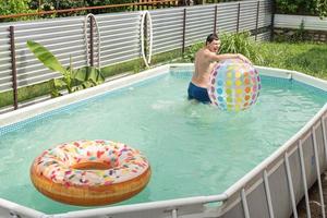 Mann hat Spaß im Schwimmbad und spielt mit aufblasbarem Ball foto