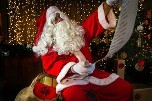 Santa claus lesen das aufführen von Weihnachten Geschenke zu Sein geliefert foto