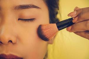 Schönheitsgesicht der asiatischen Frau durch Auftragen von Bürsten auf die Haut durch Kosmetik. foto