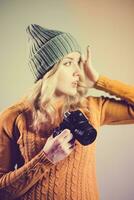 ein schön Frau Fotograf im ein gestrickt Hut ist fotografiert mit ein Kamera im ihr Hände im ein Foto Studio