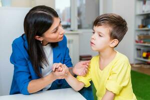 ein Frau Rede Therapeut Angebote mit das Kind und unterrichtet ihm das richtig Aussprache und kompetent Rede. foto
