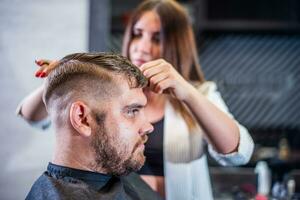 Mädchen Friseur trocknet Haar zu ein Mann im ein Salon foto