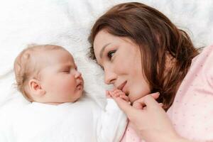jung schön Frau halten klein Hand von ihr Schlafen Baby Tochter im Schlafzimmer foto