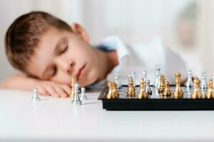 das Kind gespielt Schach und fiel schlafend beim das Tabelle foto