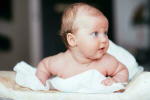 glücklich Baby Mädchen Lügen auf ein Weiß Blatt im ihr Zimmer foto