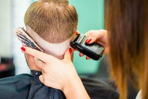 Mädchen Friseur trocknet Haar zu ein Mann im ein Salon foto