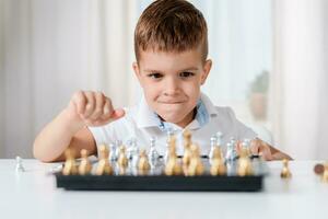 Clever Junge lernt zu abspielen Schach durch selbst im seine Zimmer beim Zuhause foto