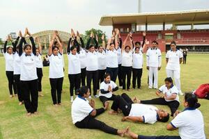 Neu Delhi, Indien, Juni 21, 2023 - - Gruppe Yoga Übung Session zum Menschen beim Yamuna Sport Komplex im Delhi auf International Yoga Tag, groß Gruppe von Erwachsene Teilnahme Yoga Klasse im Kricket Stadion foto