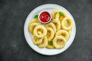 Zwiebel Ringe im Teig tief Friteuse Tomate Soße schnell Essen köstlich Essen Kochen Vorspeise Mahlzeit Essen Snack auf das Tabelle Kopieren Raum foto