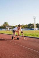 Frau auf Startposition, Vorbereitung zum Laufen auf der Stadionbahn foto