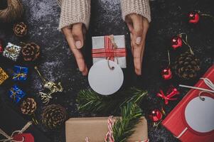 Hand, die eine schwarze Geschenkbox auf schwarzem Gipshintergrund hält foto