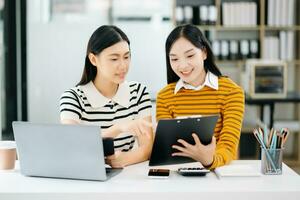 asiatisch Studenten sind studieren das Campus Park. jung Menschen sind Ausgaben Zeit zusammen. lesen Buch, Arbeiten mit Laptop, Tablette und kommunizieren während im Hochschule Bibliothek foto