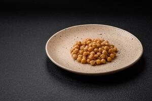 köstlich Dosen- Kichererbsen im ein Keramik Teller auf ein dunkel Beton Hintergrund foto