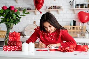 Frau schreibt Liebesbrief sitzend in der dekorierten Küche foto