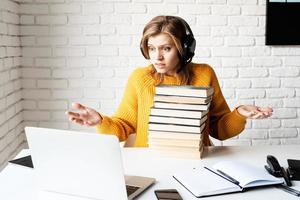 unglückliche Frau, die online studiert und einen Stapel Bücher hält