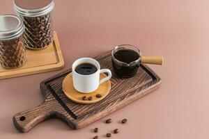 ein klein Kaffee Tasse auf ein hölzern Untertasse und ein Kaffee Topf mit frisch gebraut Kaffee Stand auf ein texturiert braun Tafel. ein köstlich trinken. foto