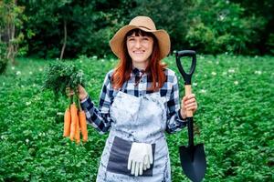 Frau mit Karotten und Schaufel foto