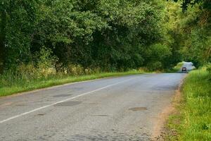 Reisen durch Wagen. Asphalt Straße unter Sommer- Felder von Grün Pflanzungen foto