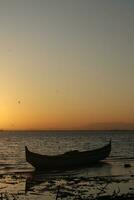 Boot im das See beim Sonnenuntergang. Rudern Boot schwebend Über das Schwebe See Gewässer. Gorontalo, Indonesien foto