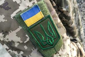 Nahansicht Textur Pixel tarnen Militär- Uniform von das bewaffnet Kräfte, Chevron Dreizack und Flagge von Ukraine foto