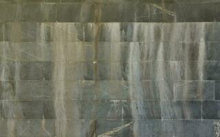 die Textur einer Wand aus großen Granitfliesen, die mit weißen Streifen bedeckt sind, wenn sie Feuchtigkeit ausgesetzt sind foto