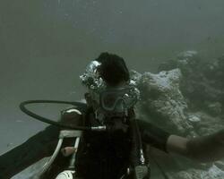 ein Mann unter das Ozean ist gesehen getragen das Sauerstoff Maske und das Tauchen Zubehör foto