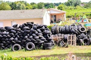 ein Stapel von Reifen im ein Feld in der Nähe von ein Haus foto