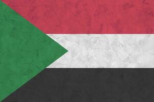 sudan-flagge in hellen farben auf alter reliefputzwand dargestellt. strukturierte Fahne auf rauem Hintergrund foto