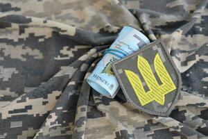 ukrainisch Heer Symbol und Bündel von Griwna Rechnungen auf Militär- Uniform. Zahlungen zu Soldaten von das ukrainisch Armee, Gehälter zu das Militär- foto