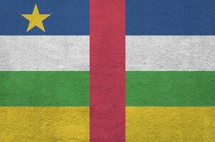 die flagge der zentralafrikanischen republik ist in hellen farben auf der alten reliefputzwand dargestellt. strukturierte Fahne auf rauem Hintergrund foto