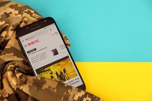 Kiew, Ukraine - - 4 dürfen, 2023 Fokus ukrainisch Nachrichten Portal auf Smartphone Bildschirm mit ukrainisch Flagge und tarnen Stoff foto