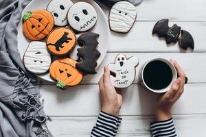 Frau bereitet sich auf Halloween vor, trinkt Kaffee mit Lebkuchen foto