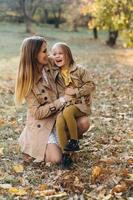Mutter und ihre Tochter sitzen und haben Spaß im Herbstpark. foto