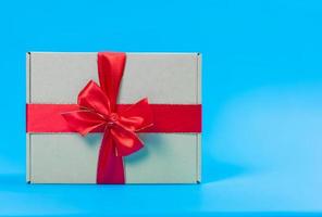 Geschenkbox mit rotem Band auf blauem Hintergrund foto
