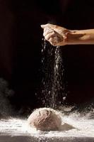Hand gießt Mehl gebackenes Brot. Auflösung und hochwertiges schönes Foto