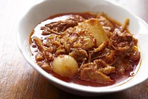 rotes Schweinefleisch-Curry auf Holztisch foto