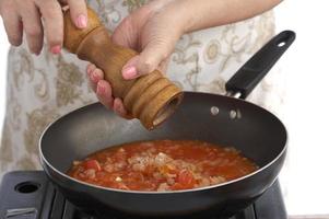 Tomatensauce in schwarzer Pfanne auf weißem Hintergrund foto