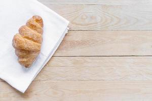 Draufsicht frisches Croissant auf weißem Stoff mit Holztisch foto