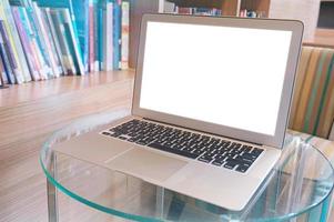 Laptop mit leerem Bildschirm auf Holztisch vor Bibliothek foto