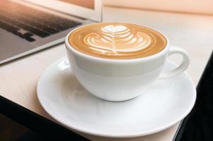Tasse heiße Latte Art mit Zimtkaffee auf Holztisch. foto