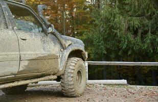 Rad Nahansicht im ein Landschaft Landschaft mit ein Schlamm Straße. Offroad 4x4 suv Automobil mit ditry Körper nach Fahrt im schlammig Straße foto