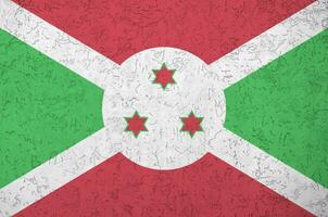 burundi-flagge in hellen farben auf alter reliefputzwand dargestellt. strukturierte Fahne auf rauem Hintergrund foto