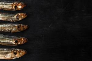 geräucherter Sprottenfisch goldbraun auf schwarzem Hintergrund foto