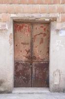 beschädigtes altes Betonhaus und rote Holztür foto
