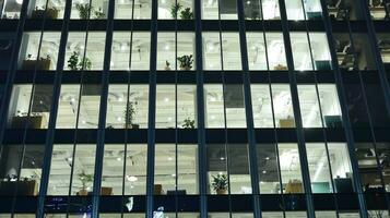 Muster von Büro Gebäude Fenster beleuchtet beim Nacht. Glas die Architektur , Unternehmen Gebäude beim Nacht - - Geschäft Konzept. foto