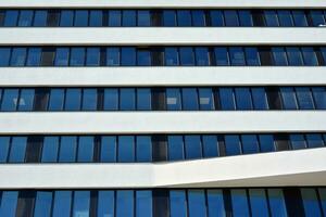 modern Büro Gebäude im das Stadt mit Fenster und Stahl und Aluminium Paneele Mauer. zeitgenössisch kommerziell die Architektur, Vertikale konvergieren geometrisch Linien. foto