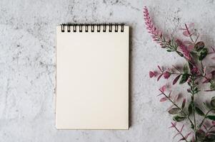 Notizbuch und Blume wird auf weißem Hintergrund platziert foto